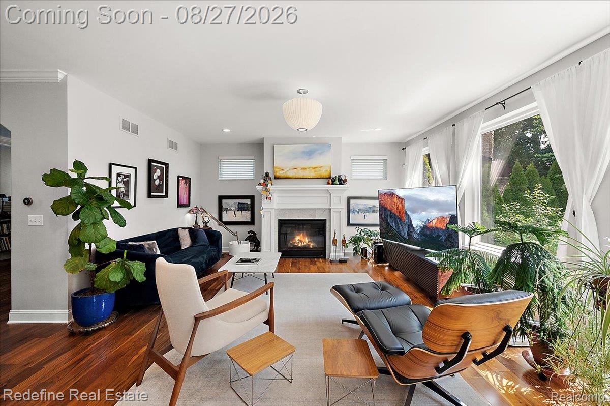 Hardwood flooring, fireplace with a decorative mantel, large windows with trim, recessed lighting, and a contemporary ceiling fixture