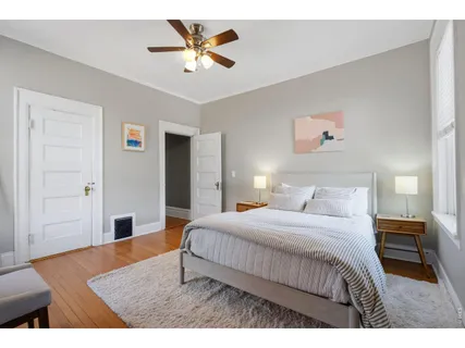 a bedroom with a bed a rug and painting on the wall