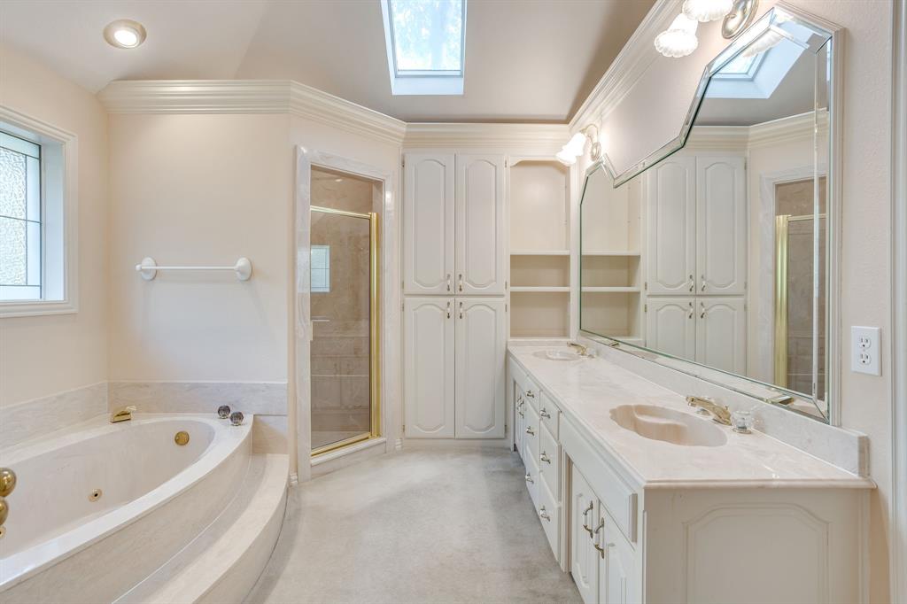 3068 High Ridge Drive Grapevine, TX 76051 - Photo 20 of 40 Dual vanity with integrated sinks, built-in cabinetry, jetted soaking tub with steps, glass-enclosed shower, and skylight