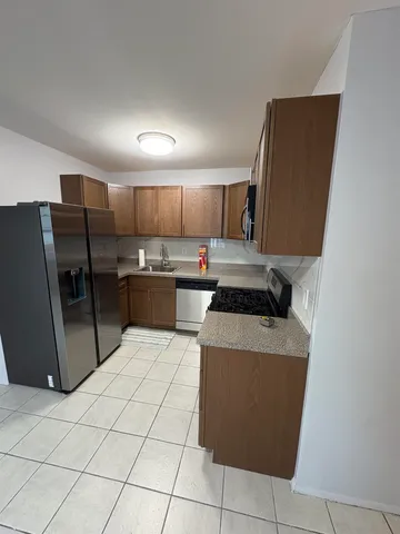 a kitchen with stainless steel appliances granite countertop a refrigerator stove a sink and a oven