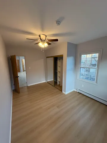 a view of an empty room with window and wooden floor