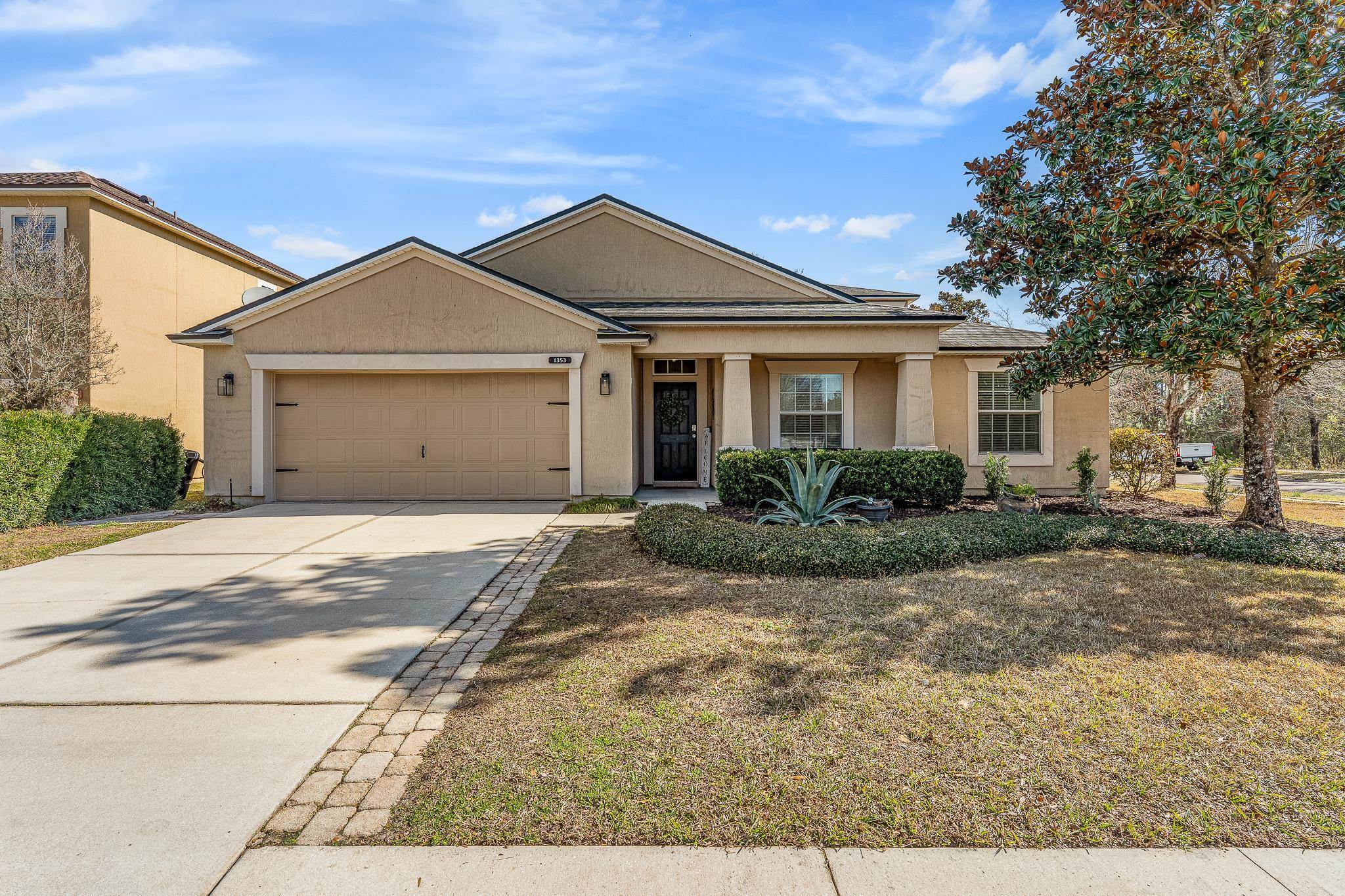 View of front facade featuring stucco siding, driveway, a garage, and a front yard