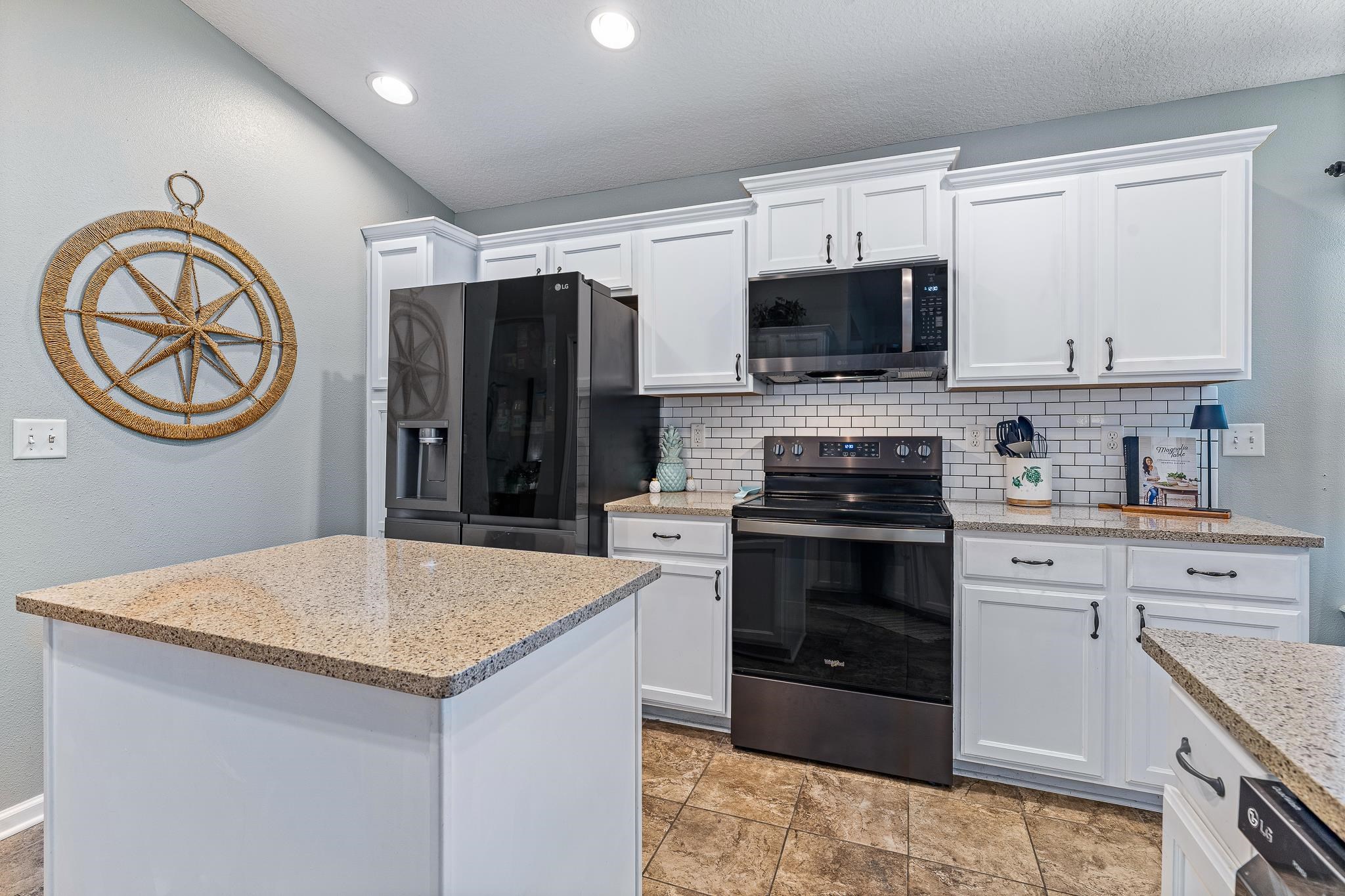 1353 Camp Ridge Lane Middleburg, FL 32068 - Photo 26 of 88 Kitchen featuring black appliances, white cabinets, light stone counters, backsplash, and a kitchen island