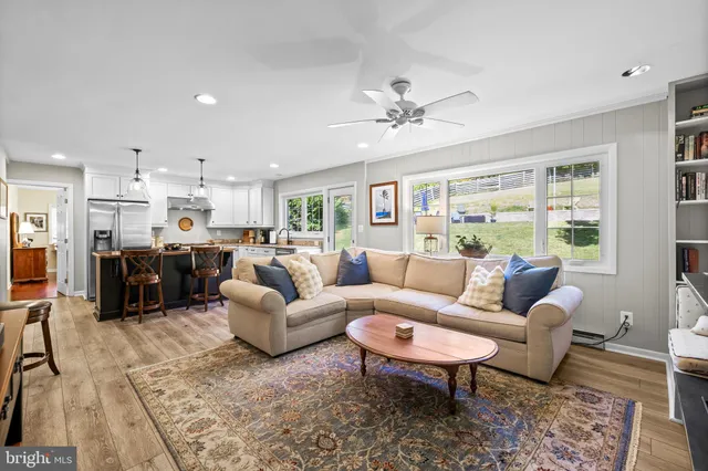 a living room with furniture kitchen view and a large window
