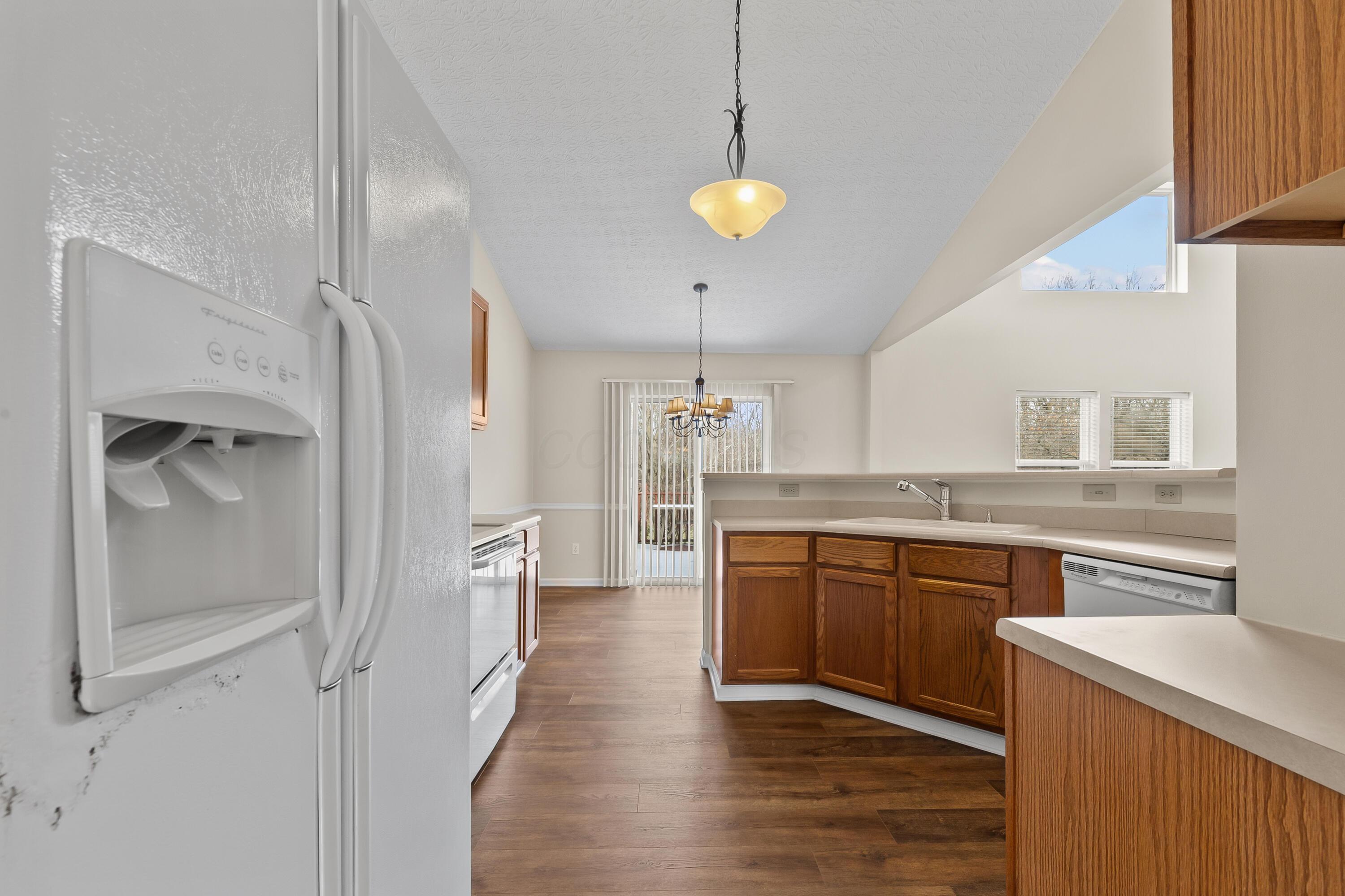 30 Tabilore Loop Delaware, OH 43015 - Photo 21 of 55 • New luxury vinyl plank flooring ~ 2025 • Tan painted walls • Oak framed cabinets • Double bowl sink with sprayer • Vaulted ceiling • Frigidaire® refrigerator • Frigidaire® electric range • Frigidaire® dishwasher • General Electric® microwave • Breakfast bar ledge • Chandelier • Step-in pantry closet