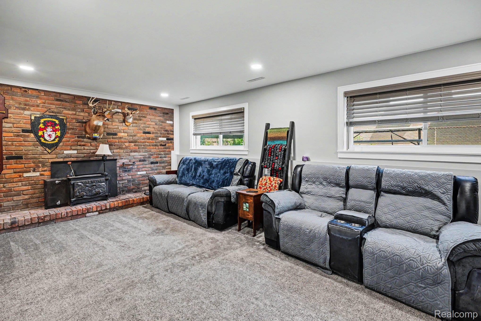 Living area featuring a brick accent wall with a hearth and a wood-burning stove