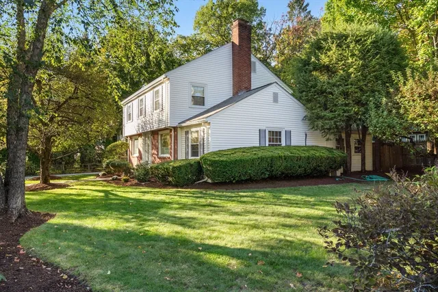 a view of a house with a big yard and potted plants and large trees