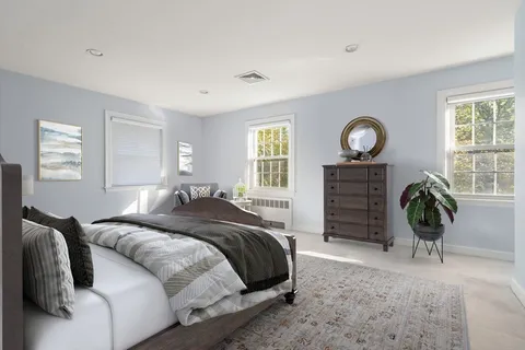 a bedroom with a bed a dresser and a large window