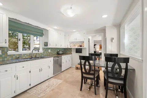 a kitchen with granite countertop chairs and white cabinets