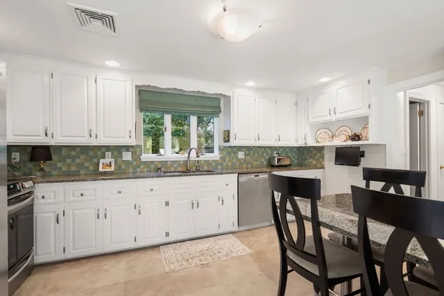 a kitchen with granite countertop white cabinets and stainless steel appliances
