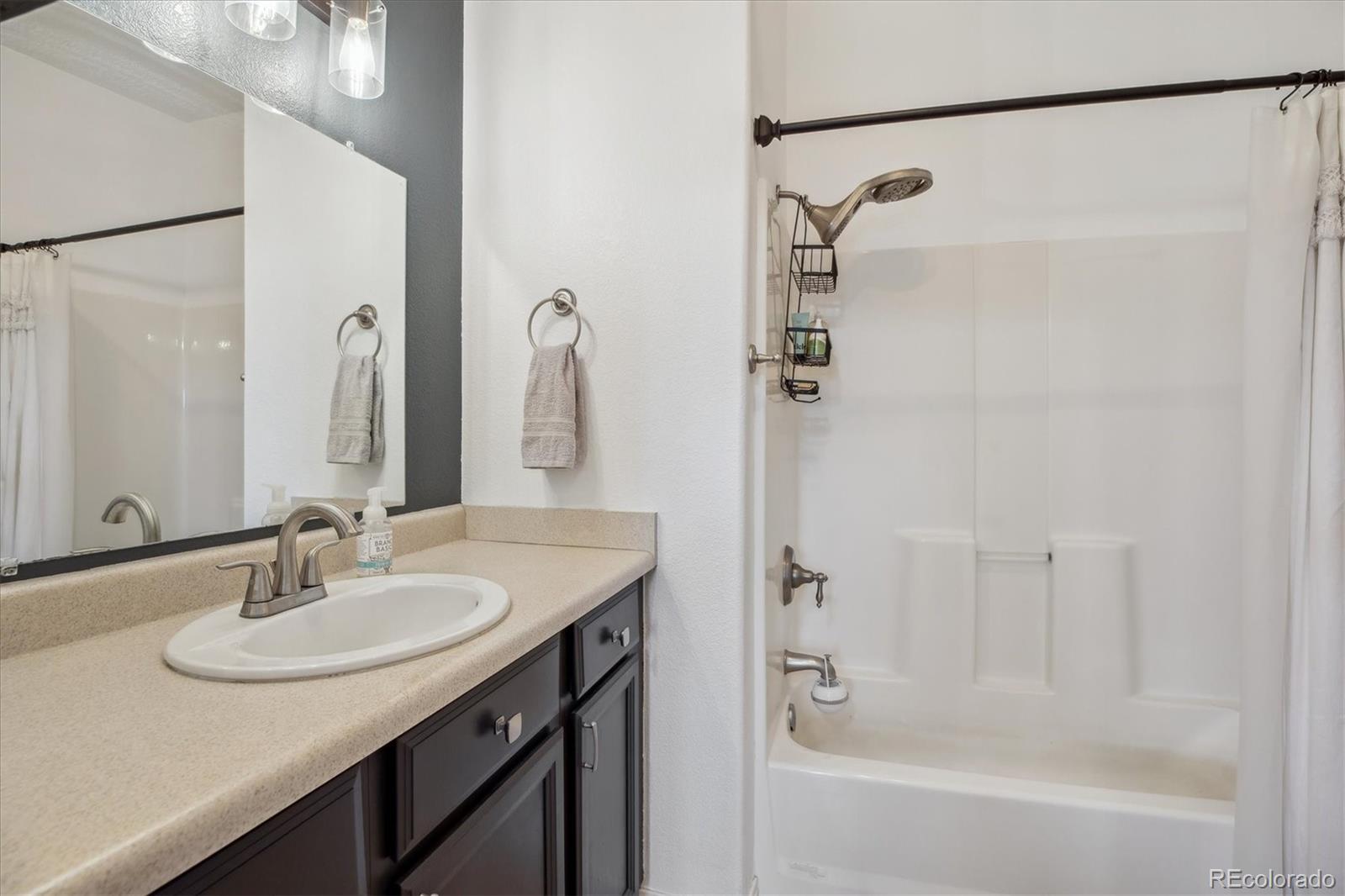 645 Yuma Loop, Unit 103 Kiowa, CO 80117 - Photo 18 of 23 a bathroom with a granite countertop sink a mirror a vanity and a bathtub