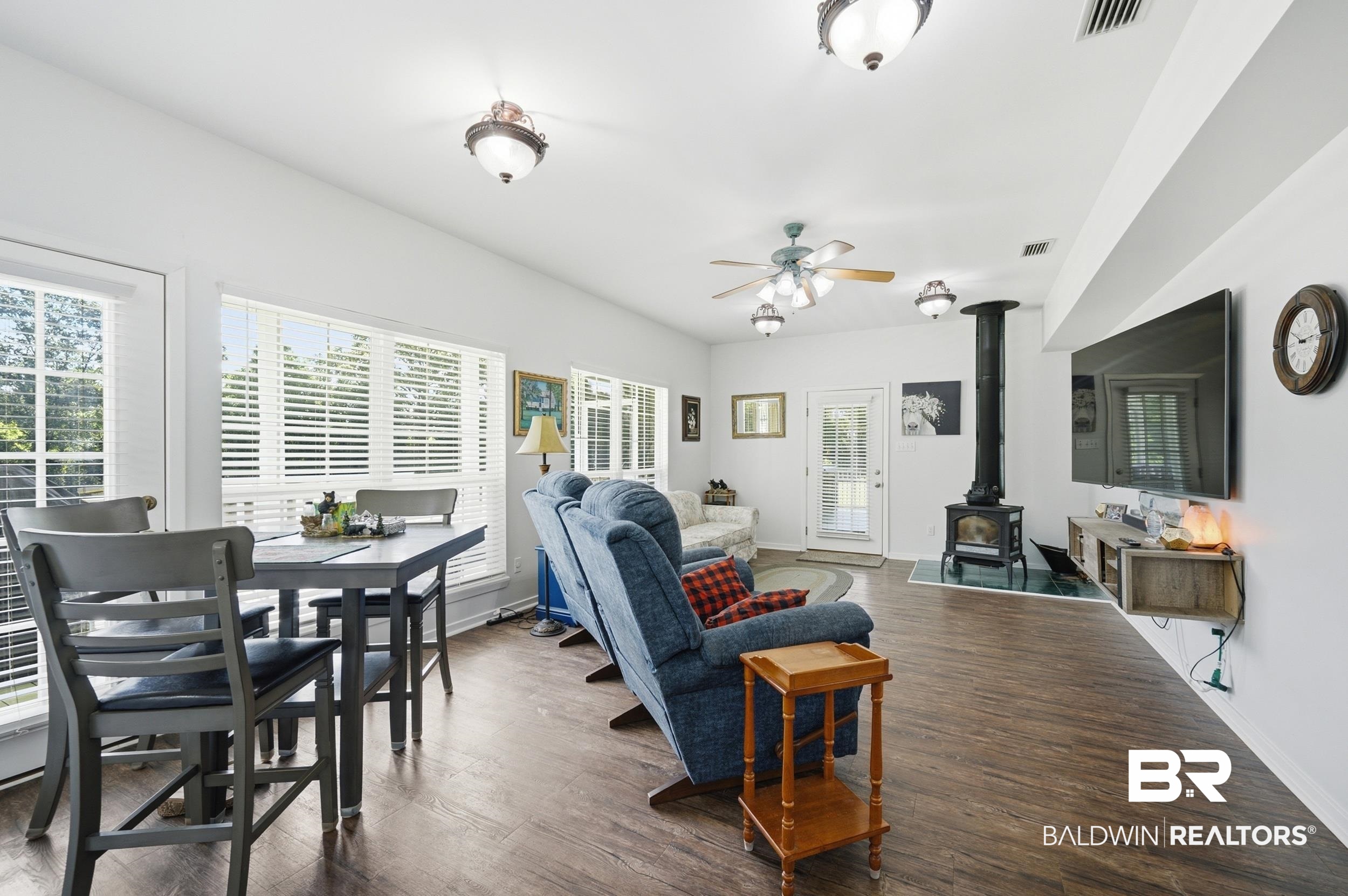 15855 Calvin Richerson Road Bay Minette, AL 36507 - Photo 31 of 83 Spacious living area featuring wood-finish flooring, a freestanding wood-burning stove, and multiple windows with white blinds