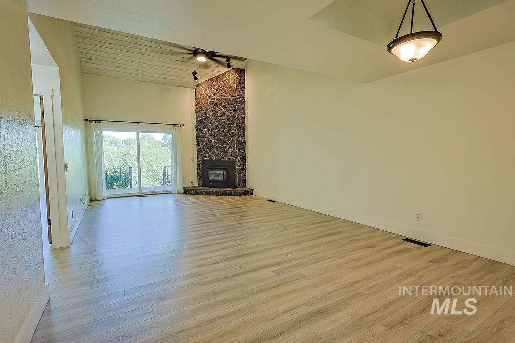 640 Morrison Street Twin Falls, ID 83301 - Photo 13 of 30 Spacious living area featuring wood-finish flooring, a vaulted ceiling with exposed white-washed wood planks, and a stone-faced fireplace with an insert