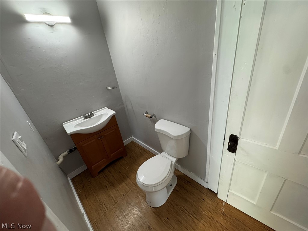 674-676 Carlysle Street Akron, OH 44310 - Photo 6 of 20 Half bathroom featuring a wood-finish floor, white toilet, and a vanity with a white sink