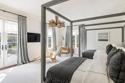 a bedroom with a bed large window and a flat tv screen