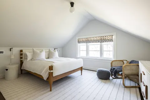 a spacious bedroom with a bed and a chair