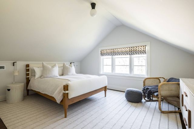 a spacious bedroom with a bed and a chair