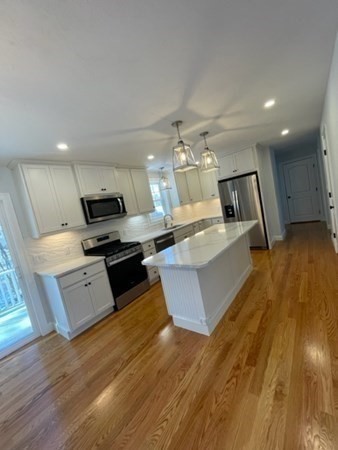 39 Staples Street Billerica, MA 01821 - Photo 5 of 25 a large kitchen with stainless steel appliances a large counter top a stove and a wooden floors