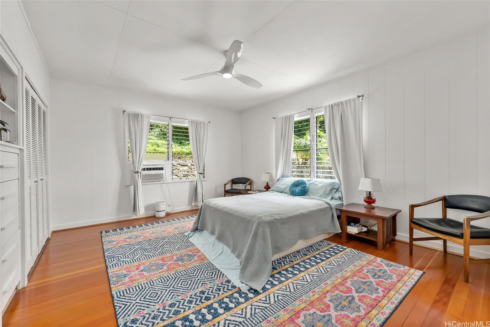 2811 Henry Street Honolulu, HI 96817 - Photo 11 of 25 Retreat to the primary bedroom, a serene sanctuary featuring brilliant natural light, warm wood floors, and a cooling ceiling fan.