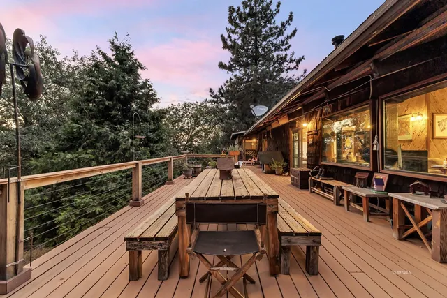 a view of a roof deck with table and chairs a barbeque with wooden floor and fence