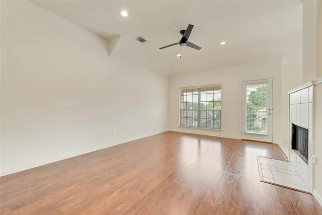 an empty room with wooden floor fan and windows