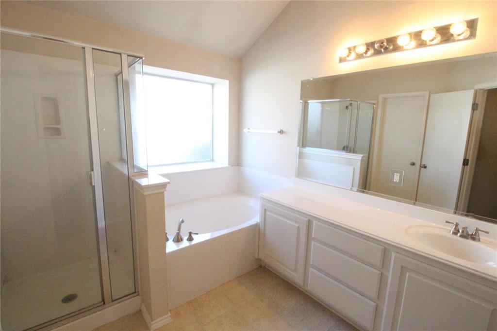 107 Inman Drive Hutto, TX 78634 - Photo 11 of 19 Spacious bathroom featuring a built-in soaking tub, separate glass-enclosed shower, expansive vanity with integrated sink, large wall-mounted mirror, and tile flooring