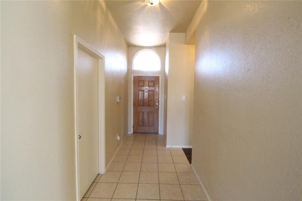 107 Inman Drive Hutto, TX 78634 - Photo 14 of 19 Foyer featuring a wood-panel entry door with an arched transom window, ceramic tile flooring, and neutral wall tones