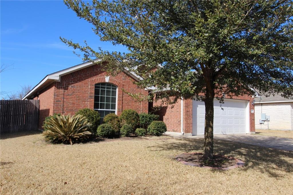 107 Inman Drive Hutto, TX 78634 - Photo 2 of 19 Brick facade residence featuring an arched window, attached garage, and mature tree
