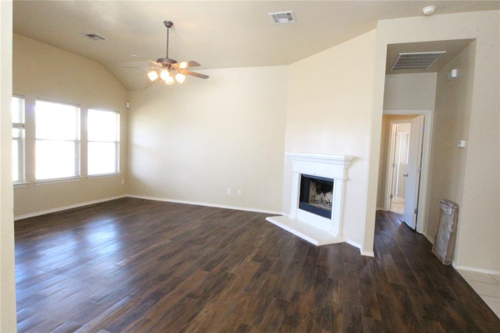 107 Inman Drive Hutto, TX 78634 - Photo 6 of 19 Spacious living area featuring wood-finish flooring, a vaulted ceiling, and multiple windows