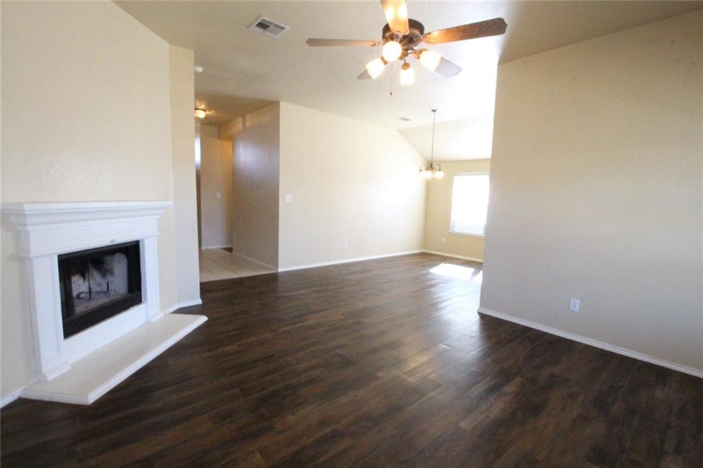 107 Inman Drive Hutto, TX 78634 - Photo 8 of 19 Living area featuring a fireplace with a white mantel, wood-finish flooring, and a ceiling fan