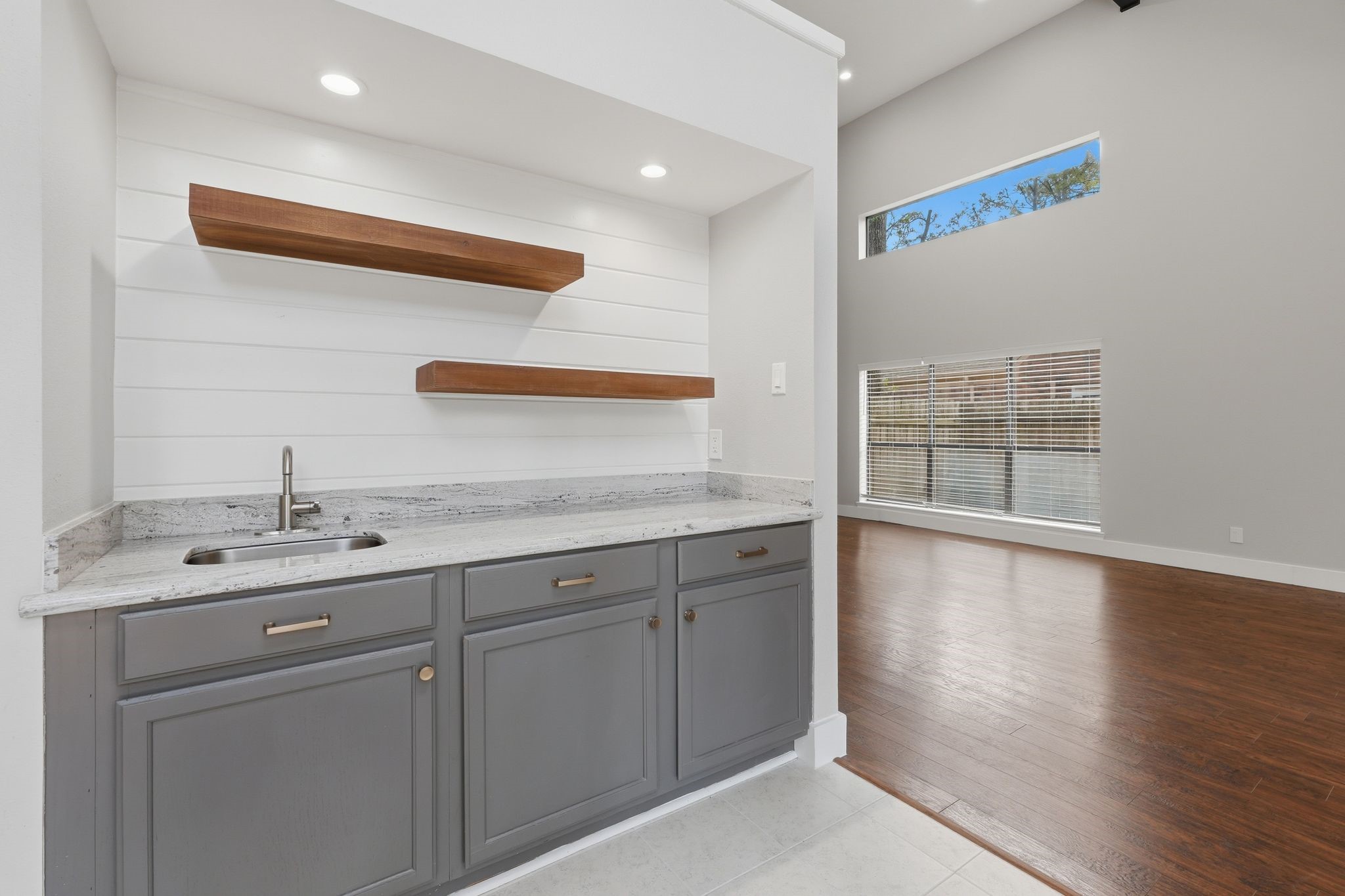 14 Dusky Meadow Place Spring, TX 77381 - Photo 10 of 47 Stylish built-in wet bar with floating wood shelves, granite countertops, and sink. Perfect for entertaining with a modern shiplap accent wall and open flow to the main living space.