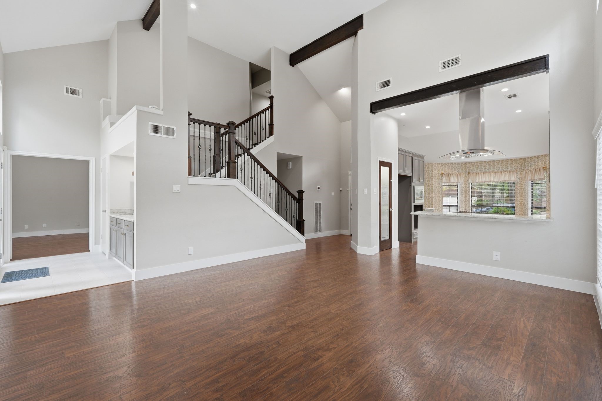 14 Dusky Meadow Place Spring, TX 77381 - Photo 11 of 47 Light-filled open-concept living space with soaring ceilings, rich wood-look flooring, and dramatic staircase. Seamless flow into the kitchen creates an ideal layout for everyday living and entertaining.