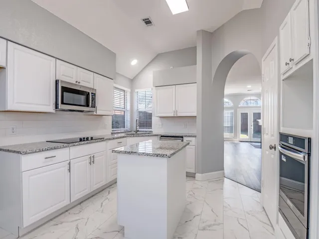 a kitchen with granite countertop a stove top oven microwave and refrigerator