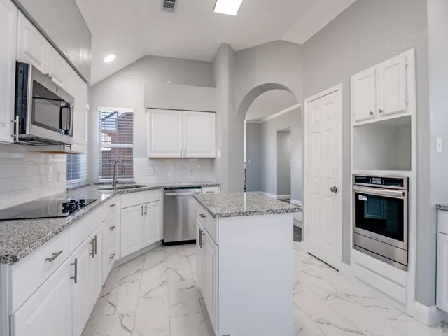 a kitchen with granite countertop a sink stainless steel appliances and cabinets
