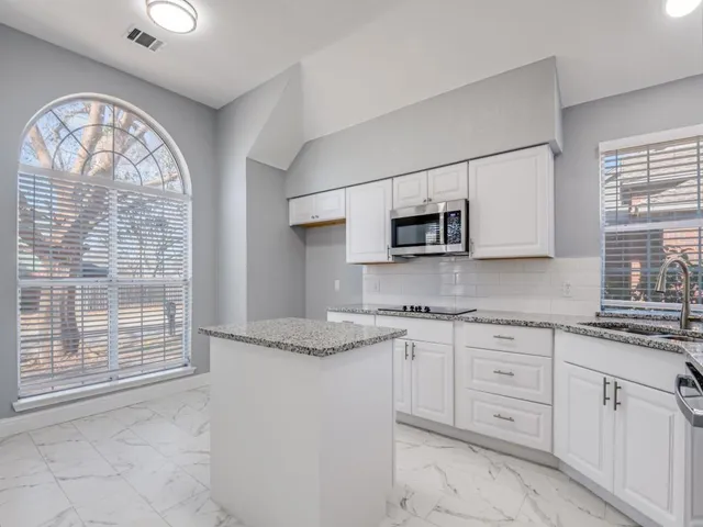 a kitchen with granite countertop white cabinets and window