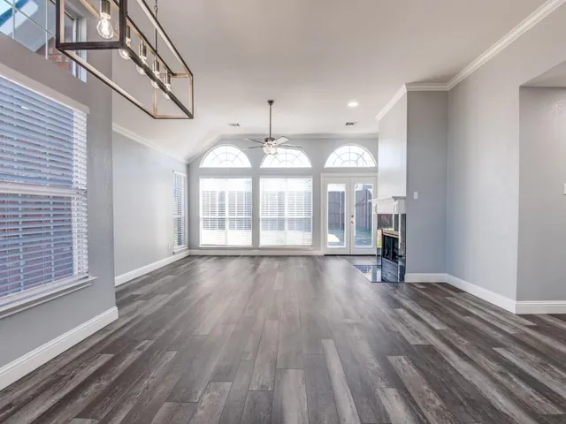 a view of an empty room with wooden floor and window
