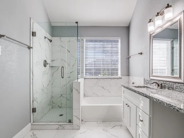a bathroom with a granite countertop tub sink shower and mirror