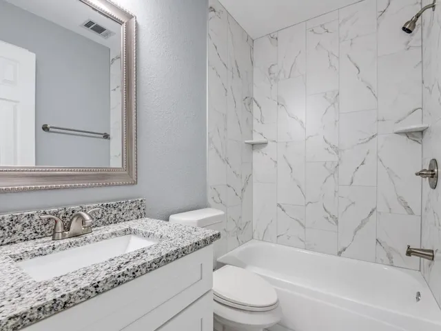 a bathroom with a granite countertop sink toilet and bathtub