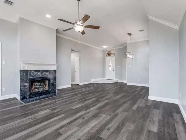 a view of an empty room with wooden floor fireplace and a window