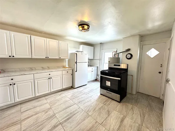 a kitchen with granite countertop a refrigerator and cabinets