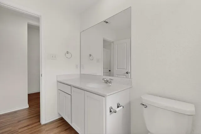 a bathroom with a granite countertop toilet a sink and a mirror