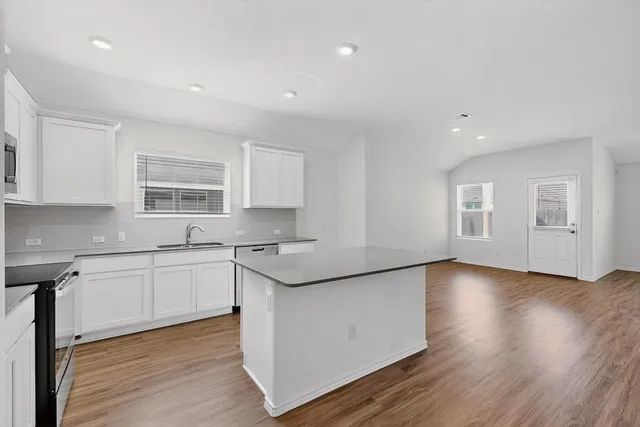a kitchen with stainless steel appliances granite countertop wooden floors and white cabinets