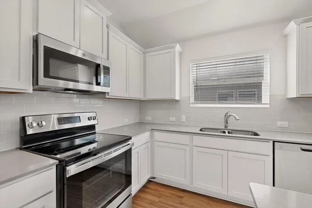 a kitchen with stainless steel appliances granite countertop white cabinets granite counter tops and a wooden floors