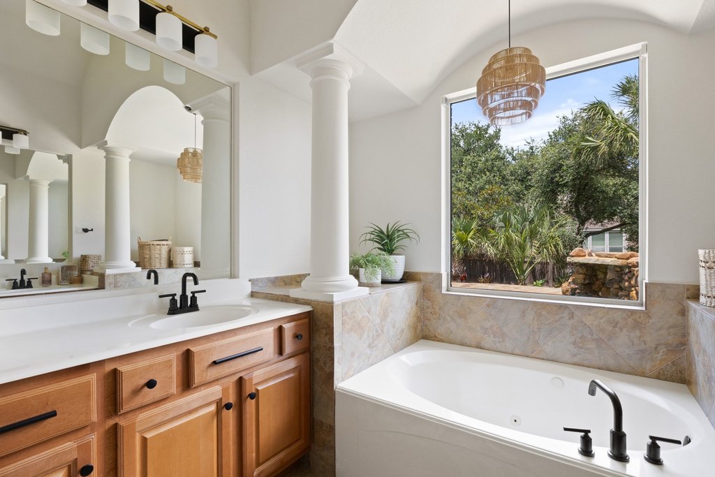 6704 Kiev Cove Austin, TX 78739 - Photo 20 of 37 Relax in this tranquil bathroom, featuring a deep soaking tub and a spacious vanity with dual sinks, all bathed in natural light.