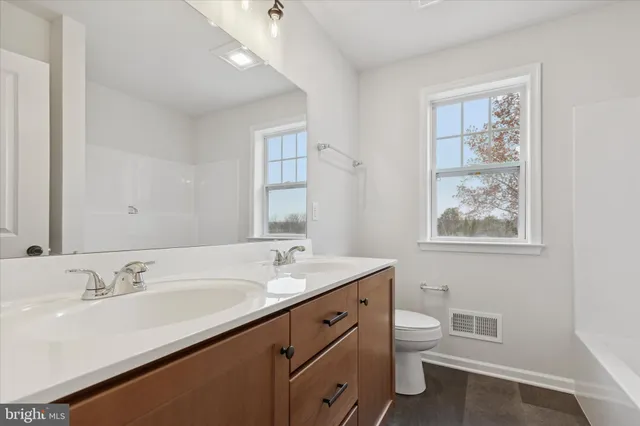 a bathroom with a granite countertop sink toilet and a mirror