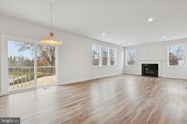 an empty room with wooden floor fireplace and windows