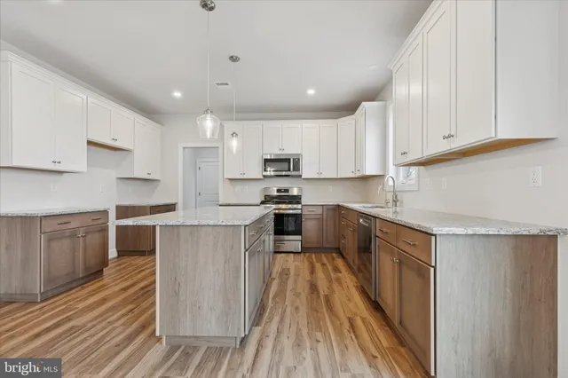 a kitchen with kitchen island granite countertop wooden floors stainless steel appliances and cabinets