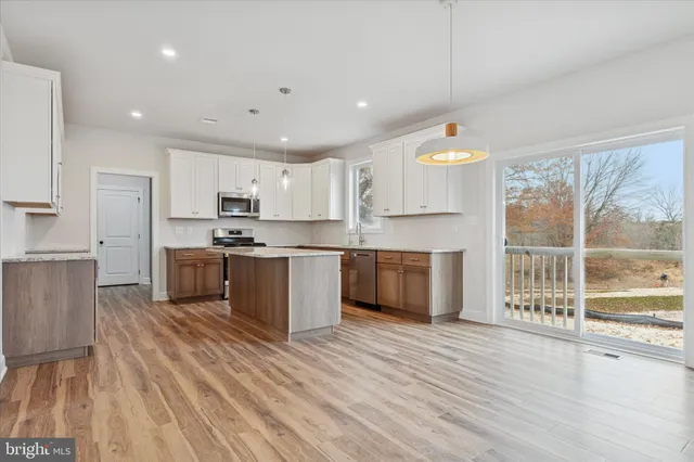 a large kitchen with stainless steel appliances granite countertop a stove a sink dishwasher and a refrigerator with wooden floor