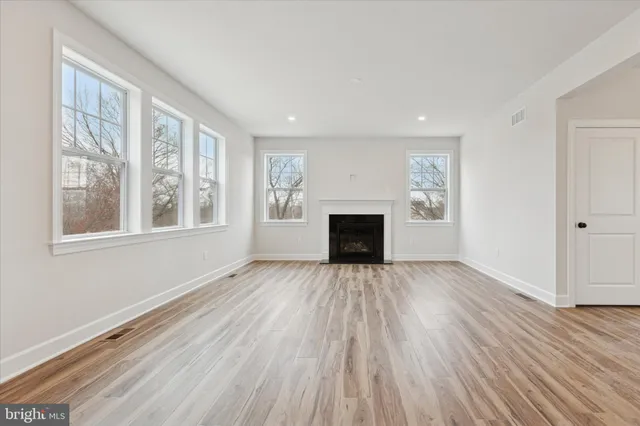 a view of empty room with wooden floor and fireplace