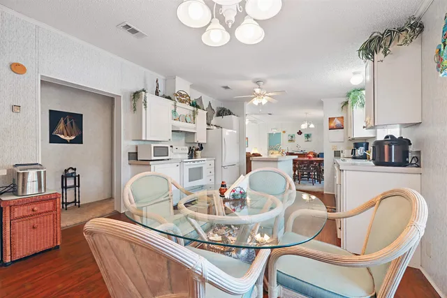 a dining room with wooden floor a chandelier a wooden table and chairs